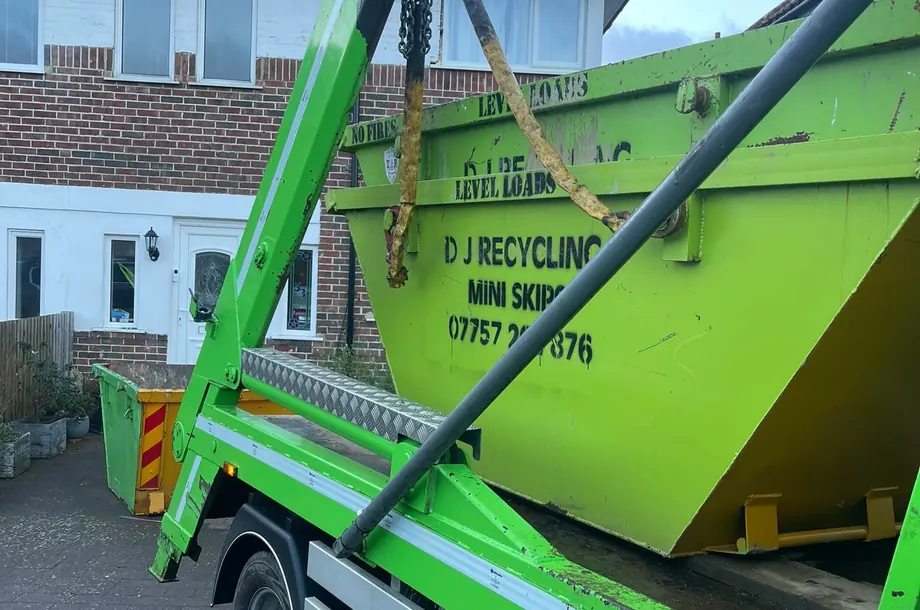 Genuine DJ Recycling mini skip being lifted on a green lorry